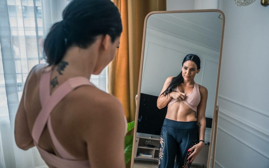 woman looking at her body in the mirror